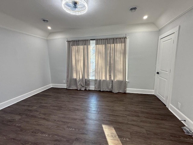 empty room featuring baseboards, vaulted ceiling, and dark wood-style flooring