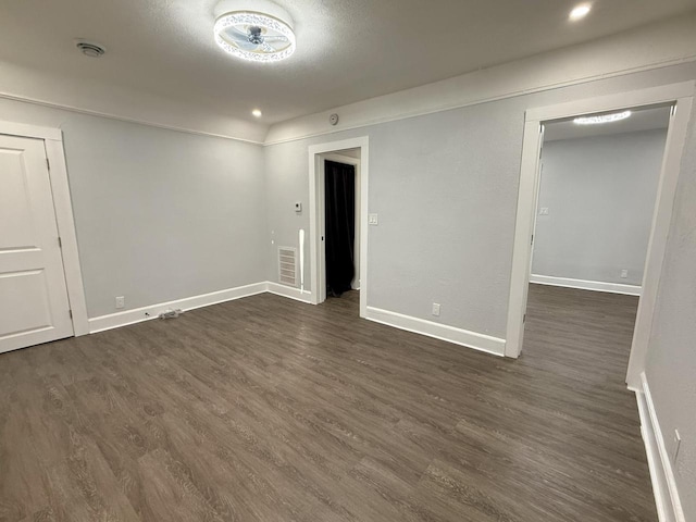 spare room featuring recessed lighting, dark wood-style flooring, visible vents, and baseboards