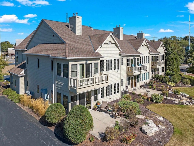 back of property with a chimney and a patio area