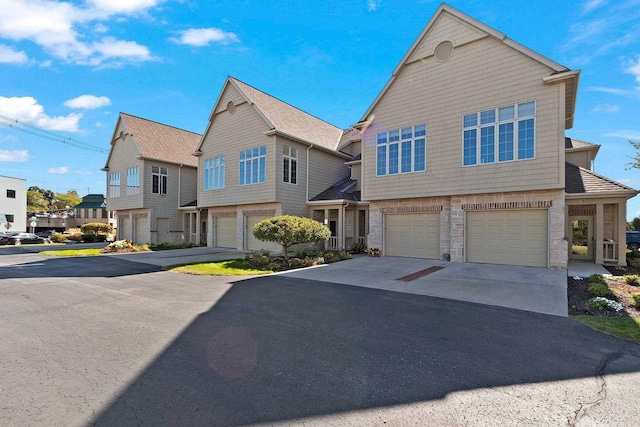 view of front of home featuring a residential view, stone siding, a garage, and driveway