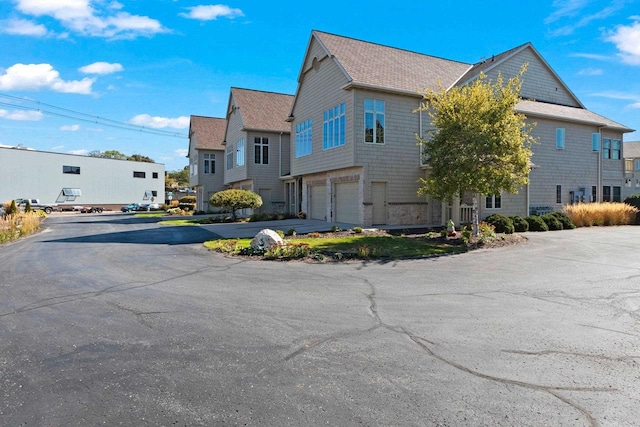 view of property exterior featuring aphalt driveway, a residential view, and an attached garage