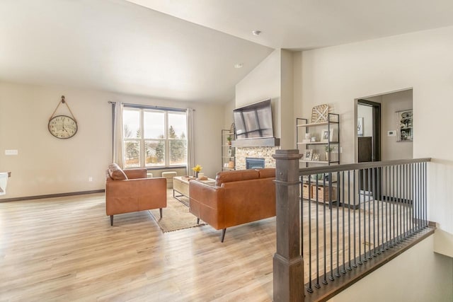 living area featuring light wood-style floors, a fireplace, high vaulted ceiling, and baseboards