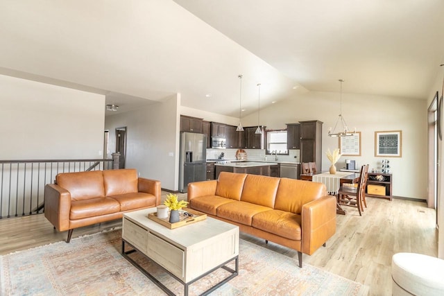 living room with light wood-style floors, baseboards, vaulted ceiling, and an inviting chandelier