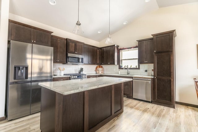 kitchen featuring decorative backsplash, appliances with stainless steel finishes, vaulted ceiling, dark brown cabinets, and a sink