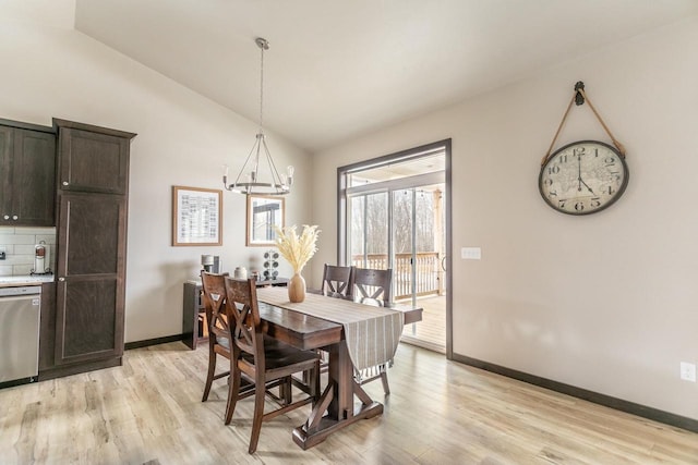 dining area featuring light wood-type flooring, baseboards, vaulted ceiling, and a chandelier