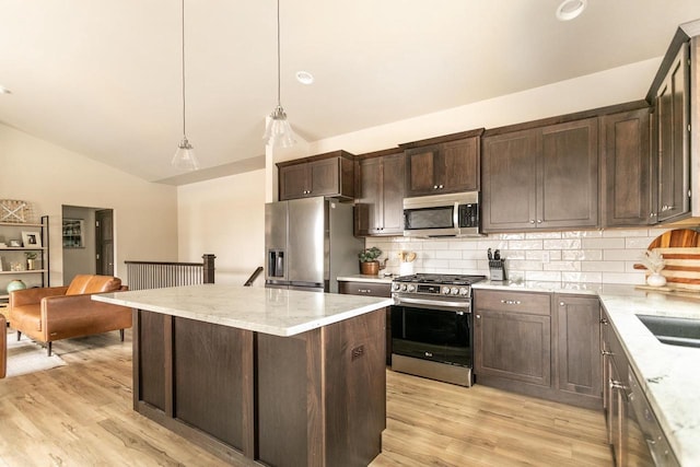 kitchen with lofted ceiling, light wood-style flooring, appliances with stainless steel finishes, dark brown cabinetry, and a kitchen island