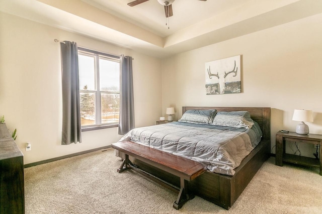 bedroom with ceiling fan, baseboards, a raised ceiling, and carpet flooring