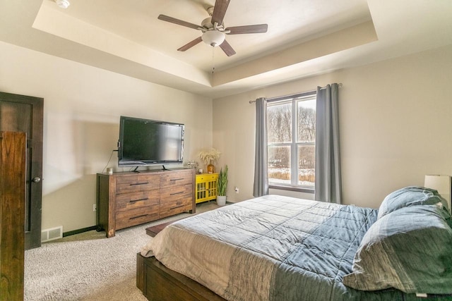 bedroom featuring carpet floors, baseboards, visible vents, and a raised ceiling