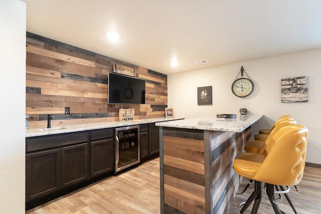 bar featuring light wood finished floors, wine cooler, visible vents, and wet bar