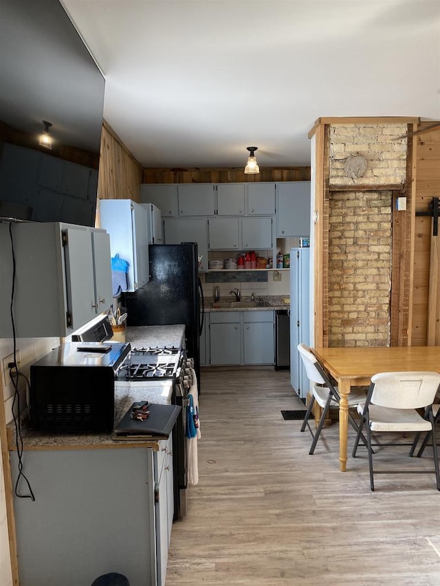 kitchen featuring light wood-style floors, dark countertops, a sink, and dishwasher