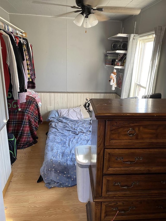 bedroom featuring light wood-style floors and a wainscoted wall