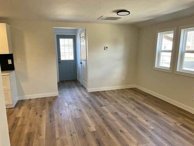 unfurnished dining area featuring visible vents, baseboards, and wood finished floors