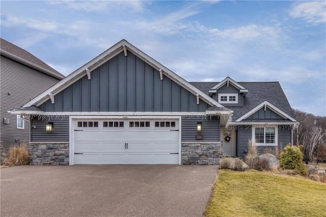 view of front of home featuring a garage, stone siding, aphalt driveway, and board and batten siding