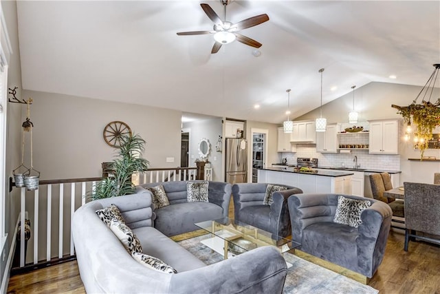 living area featuring lofted ceiling, dark wood-style flooring, and ceiling fan with notable chandelier