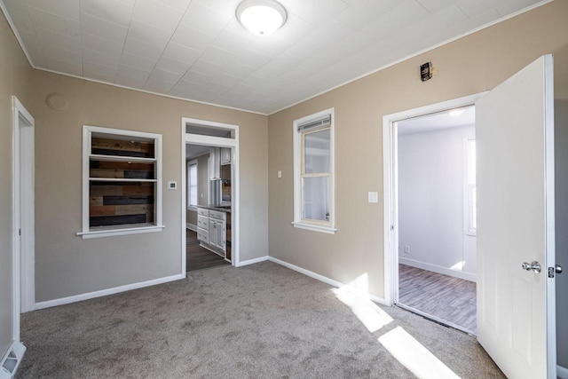 carpeted empty room featuring visible vents and baseboards