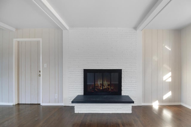 room details with wood finished floors, beamed ceiling, and a glass covered fireplace