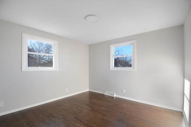 spare room with visible vents, baseboards, and wood finished floors