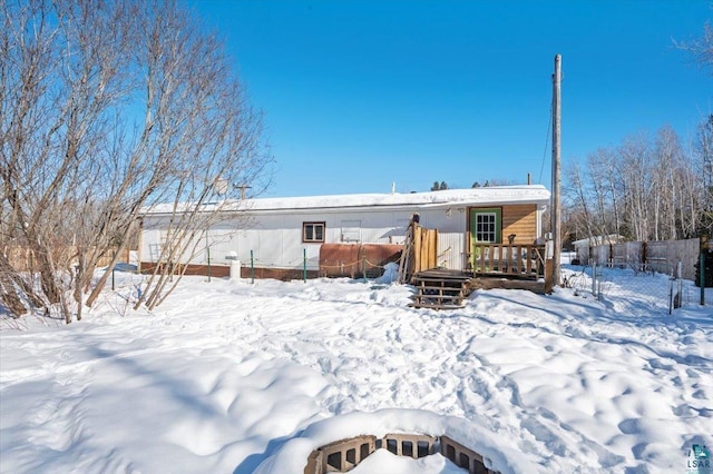 snow covered rear of property with a wooden deck