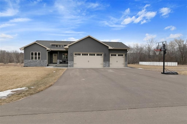 view of front of house featuring aphalt driveway, stone siding, board and batten siding, and an attached garage