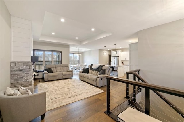 living room with a tray ceiling, wood finished floors, and recessed lighting