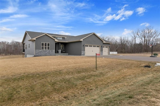 view of front facade with aphalt driveway, an attached garage, board and batten siding, stone siding, and a front lawn