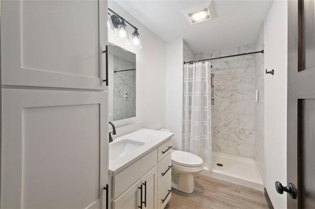 full bath featuring toilet, wood finished floors, visible vents, vanity, and a stall shower