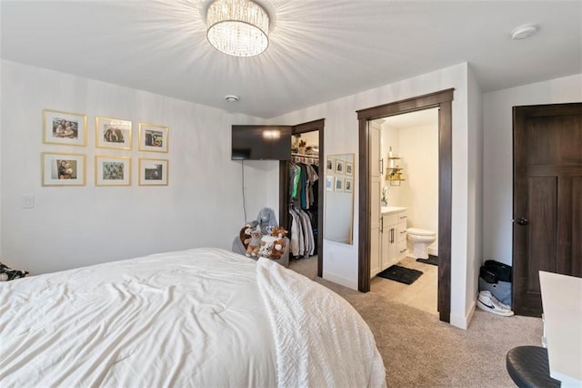 bedroom featuring light carpet, a closet, a spacious closet, and connected bathroom