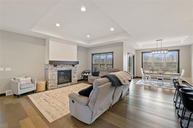 living room featuring a healthy amount of sunlight, visible vents, a raised ceiling, and dark wood-style flooring