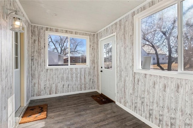 doorway featuring wallpapered walls, crown molding, baseboards, and wood finished floors