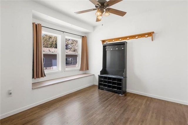 interior space with wood finished floors, a ceiling fan, and baseboards