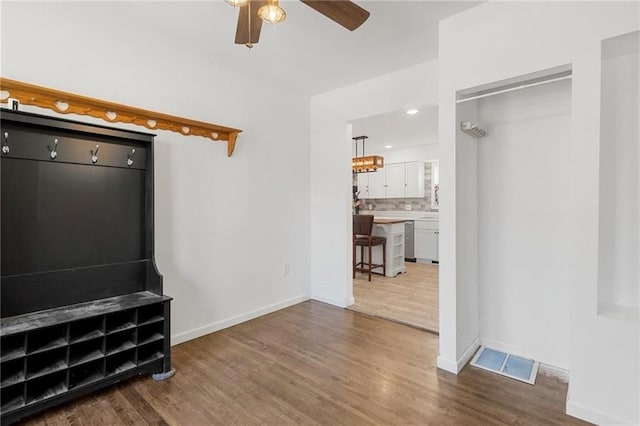 unfurnished living room featuring a ceiling fan, visible vents, baseboards, and wood finished floors