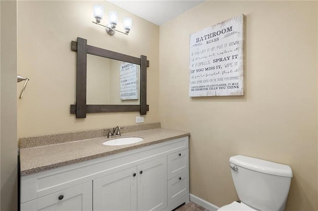 bathroom with toilet, baseboards, and vanity