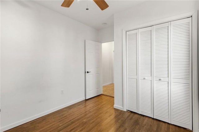 unfurnished bedroom with a ceiling fan, a closet, baseboards, and wood finished floors