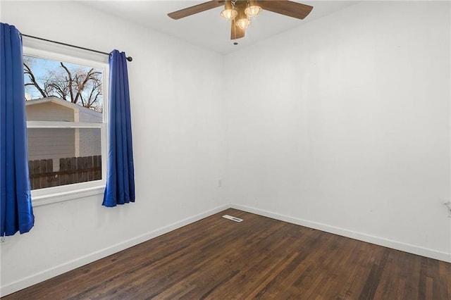 empty room featuring ceiling fan, dark wood finished floors, visible vents, and baseboards