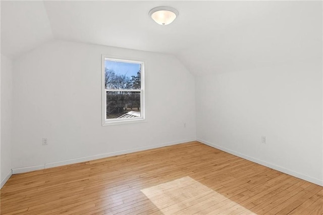 bonus room with light wood finished floors, baseboards, and vaulted ceiling