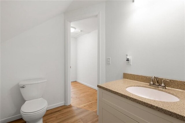 bathroom with baseboards, vanity, toilet, and wood finished floors