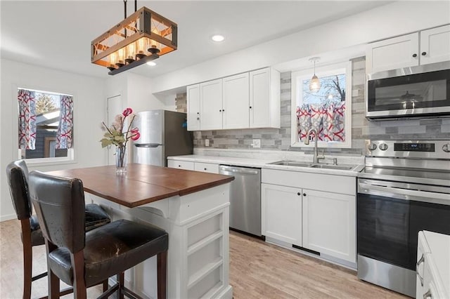 kitchen with white cabinetry, decorative backsplash, stainless steel appliances, and a sink