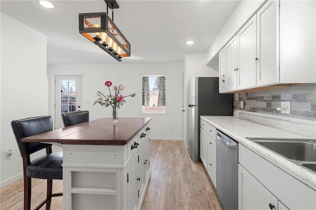 kitchen with appliances with stainless steel finishes, a healthy amount of sunlight, decorative backsplash, and white cabinets