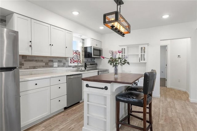 kitchen featuring white cabinets, light wood-style flooring, appliances with stainless steel finishes, and open shelves