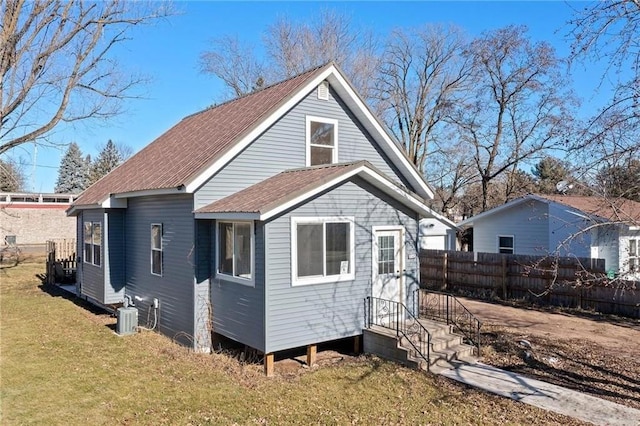 rear view of house with a lawn, cooling unit, and fence