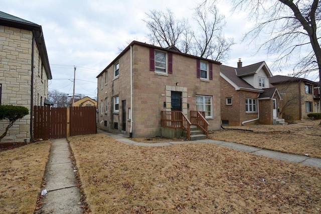 view of front of house featuring brick siding and fence