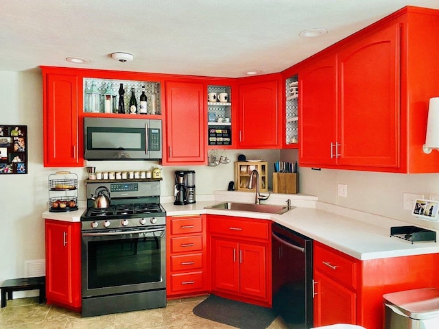 kitchen with reddish brown cabinets, stainless steel appliances, a sink, and light countertops