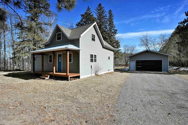 view of front of property featuring metal roof, a detached garage, a porch, and an outdoor structure