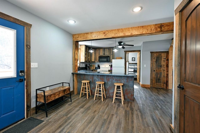 kitchen featuring a peninsula, white appliances, dark countertops, and dark wood-style flooring