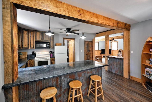 kitchen featuring a peninsula, white appliances, dark countertops, and dark wood-style floors