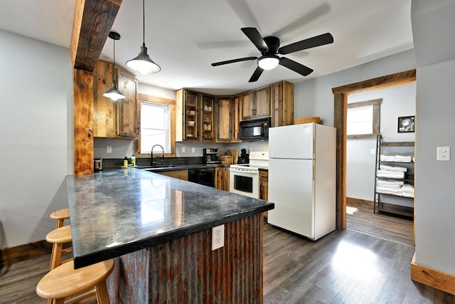 kitchen featuring dark countertops, black appliances, a peninsula, and a sink