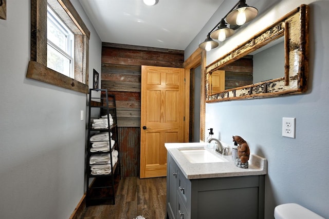 half bathroom featuring toilet, wood finished floors, and vanity