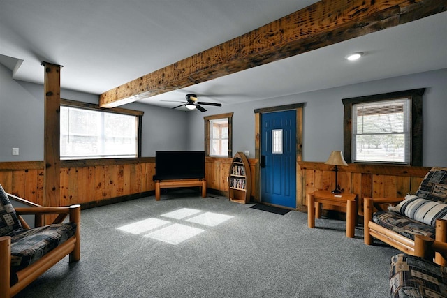 sitting room with a wainscoted wall, wood walls, beamed ceiling, and a wealth of natural light