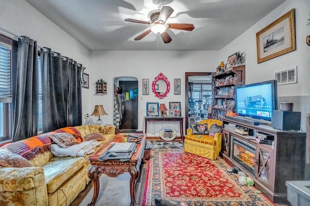 living area with arched walkways, visible vents, and ceiling fan