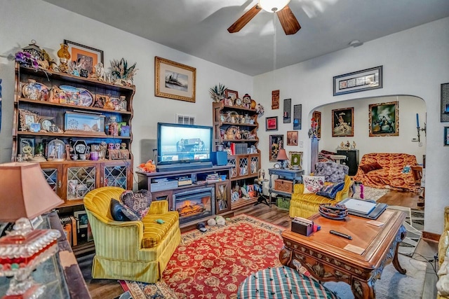 living room featuring ceiling fan, arched walkways, and wood finished floors